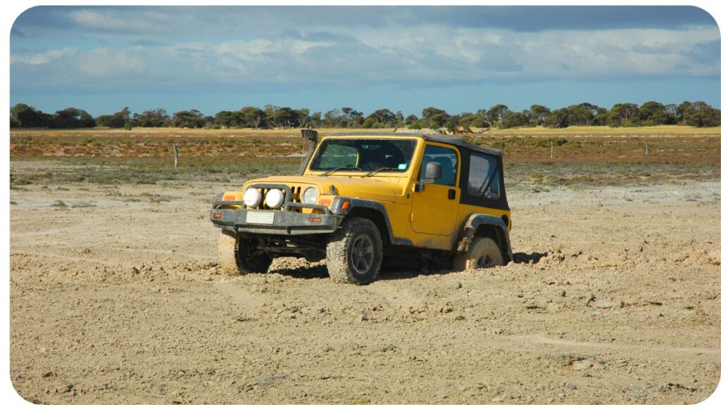a yellow jeep driving on a dirt road