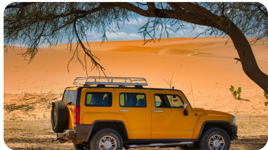 a yellow jeep parked in front of a tree in the desert