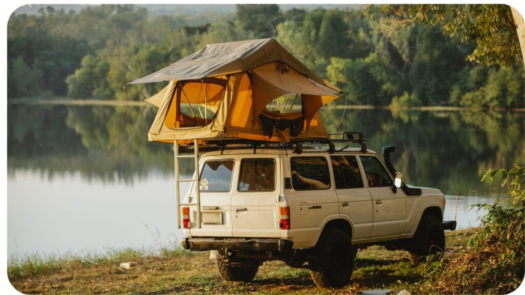 an suv with a tent on top of it parked next to a lake