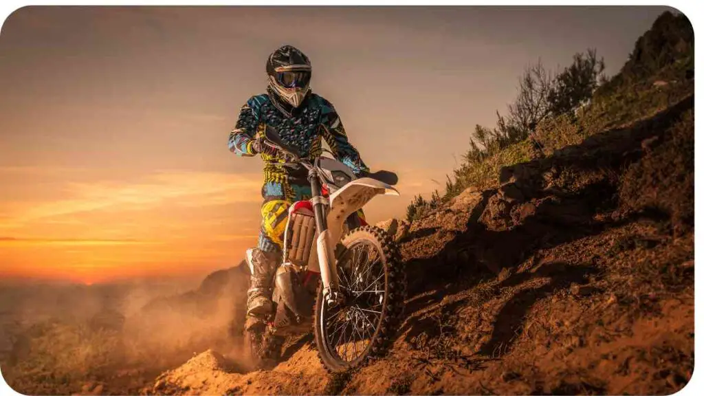 a person riding a dirt bike on a hill at sunset